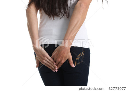 Woman with indigestion stands with back holding hand on butt Woman with indigestion stands with back holding hand on butt 82773077