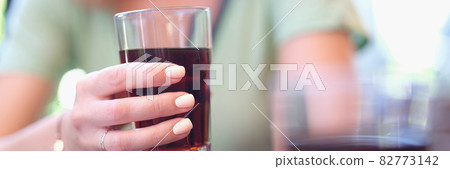 Woman hand holds glass beaker with brown liquid Woman hand holds glass beaker with brown liquid 82773142