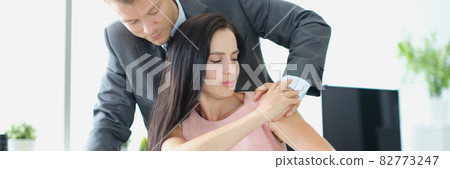 Young man in suit touching unhappy woman on shoulder in office Young man in suit touching unhappy woman on shoulder in office 82773247