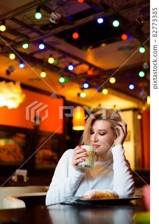 Beautiful woman drinking coffee at the cafe wintertime. Beautiful woman drinking coffee at the cafe wintertime. 82773385