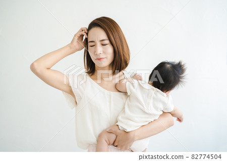 一位母親抱著嬰兒,看起來很累 一位母親抱著嬰兒,看起來很累 82774504