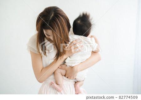 A mother holding a baby and looking tired 82774509