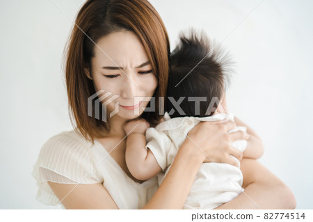 A mother holding a baby and looking tired 82774514