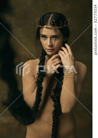Art portrait of beautiful woman in crown with long black braids tenderly looking at camera isolated over vintage background. Antique style Art portrait of beautiful woman in crown with long black braids tenderly looking at camera isolated over vintage background. Antique style 82775034