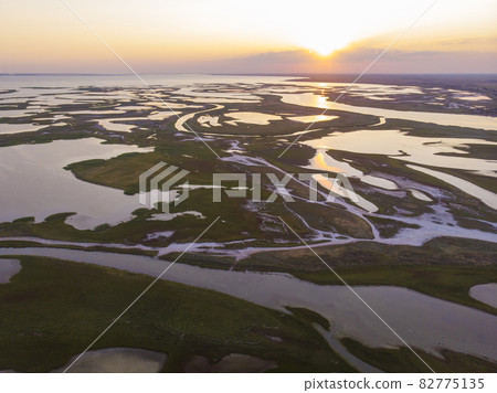 Aerial drone view of a swamp at amazing bright sunset. Aspalt Road through the Lakes and Marsh Aerial drone view of a swamp at amazing bright sunset. Aspalt Road through the Lakes and Marsh 82775135