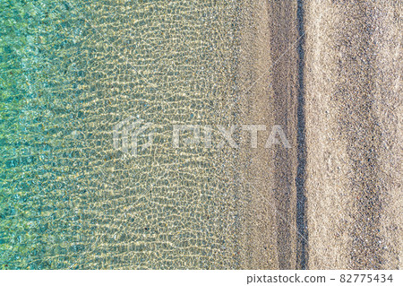 Blue, turquoise transparent water surface of ocean, sea, lagoon. Horizontal background. Top view of sand beach. Aerial, drone view 82775434