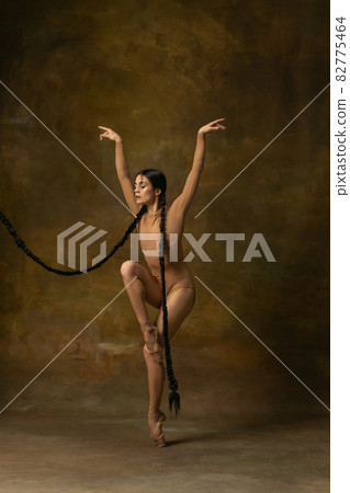 Full-length portrait of beautiful ballerina dancing, flying like a bird isolated over vintage background. Art ballet 82775464