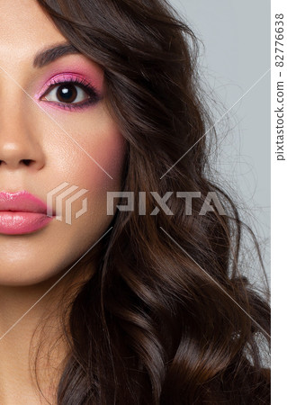 Half the face of a young sexy woman with pink lipstick on her lips and black eyeliner. Classic makeup and straight long hair. Evening make-up, cosmetology, spa, cosmetics, rejuvenation Half the face of a young sexy woman with pink lipstick on her lips and black eyeliner. Classic makeup and straight long hair. Evening make-up, cosmetology, spa, cosmetics, rejuvenation 82776638
