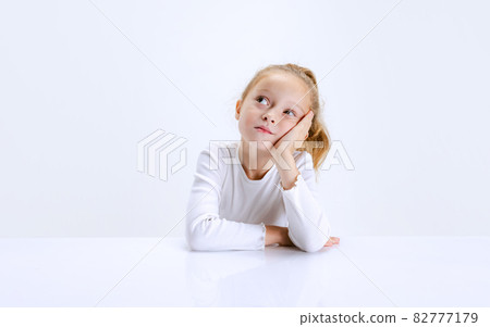 Portrait of beuatiful school girl sitting and looking at camera isolated on white background. Happy childhood, education Portrait of beuatiful school girl sitting and looking at camera isolated on white background. Happy childhood, education 82777179