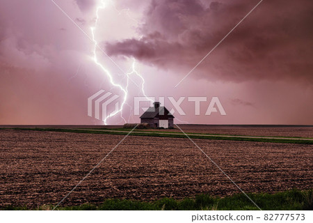 One rural barn, house in the middle in field on stormy sky with lightning strike background. 82777573