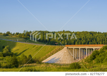 Unique concrete bridge and road against background of forest. 82778277
