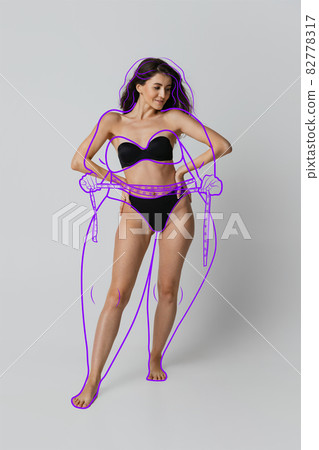 One young beautiful slim woman in lingerie isolated over gray background. Line art. Modern artwork. Healthy eating concept One young beautiful slim woman in lingerie isolated over gray background. Line art. Modern artwork. Healthy eating concept 82778317