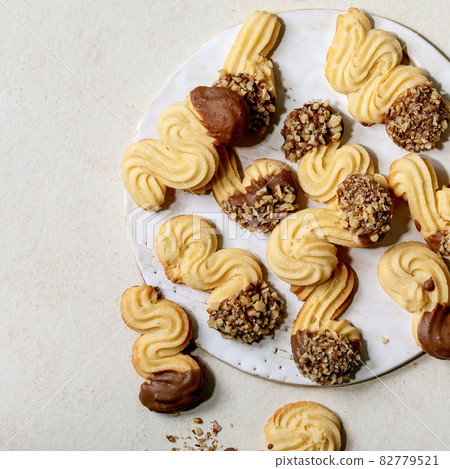 Shortcrust cookies with chocolate glaze and nuts over white. Top view 82779521