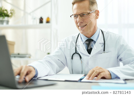 Cheerful doctor using modern notebook in clinic 82781143