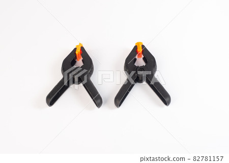 Two black construction clothespins on a white background. close-up 82781157