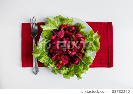 Vinaigrette on a white background. Beautifully served dish on a red napkin. Traditional Russian vegetable salad with beets on a plate. Vinaigrette on a white background. Beautifully served dish on a red napkin. Traditional Russian vegetable salad with beets on a plate. 82782260