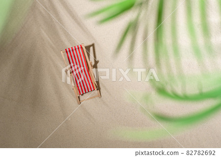 Aerial view two deck chair, glass of juice, flip flops on sand through the branches of palm and shadow palm tree. Travel, holiday, summertime, romantic concept. Top view. 82782692