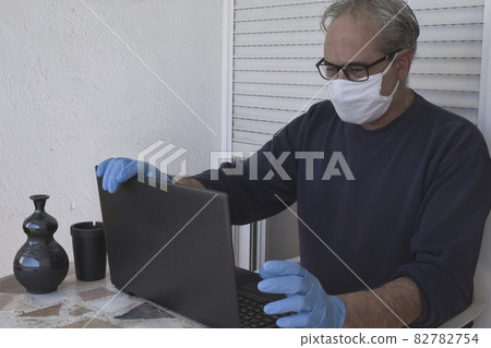 a man working with a computer wearing gloves and mask 82782754