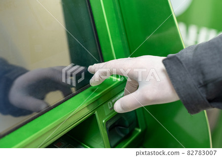 Men hand in protective rubber gloves touches the screen of an ATM during coronavirus epidemic. Pandemic. 82783007