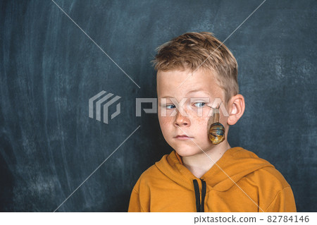 Funny kid boy portrait with Helix Pomatia snail on face. Child playing with pet giant snail. Disgusting snail. Pet at home. Take care. Boy afraid of unusual animals. Snail with brown striped shell 82784146