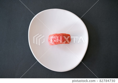 Sushi Nigiri with raw tuna served on white plate. One sushi piece on the black background. Japanese traditional food. Sushi Nigiri with raw tuna served on white plate. One sushi piece on the black background. Japanese traditional food. 82784730