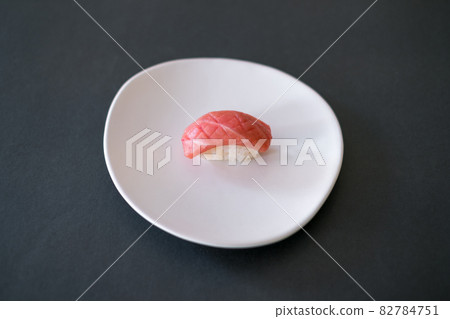 Sushi Nigiri with raw tuna served on white plate. One sushi piece on the black background. Japanese traditional food.  82784751