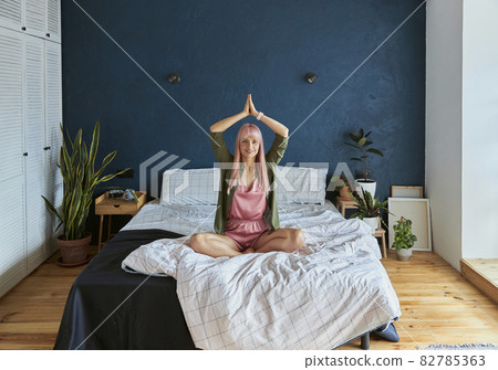 Beautiful lady with long pink hair meditates with hands in namaste mudra above head 82785363
