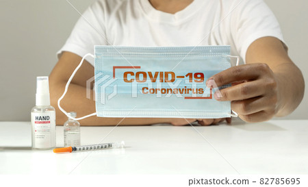 Young woman holding a mask with COVID-19 Coronavirus message on a mask for mental health care during the COVID-19 outbreak. 82785695