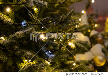 burning garland decorates christmas tree covered with snow festive background 82785759