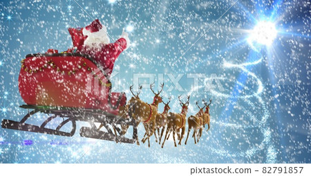 Composition of santa claus in sleigh pulled by reindeer with snow falling on blue background Composition of santa claus in sleigh pulled by reindeer with snow falling on blue background 82791857