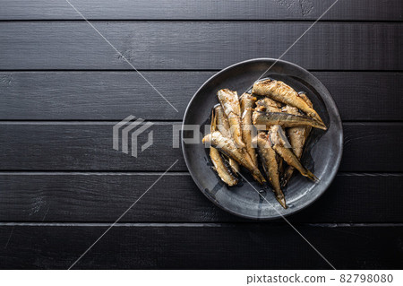 Smoked sprats on plate. Canned sea fish 82798080