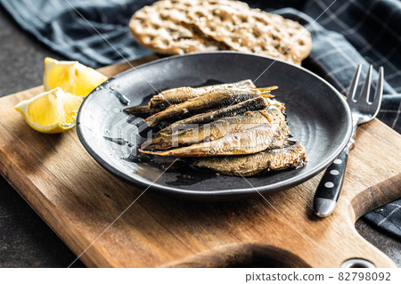 Smoked sprats on plate. Canned sea fish. 82798092