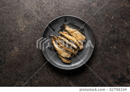 Smoked sprats on plate. Canned sea fish. 82798104