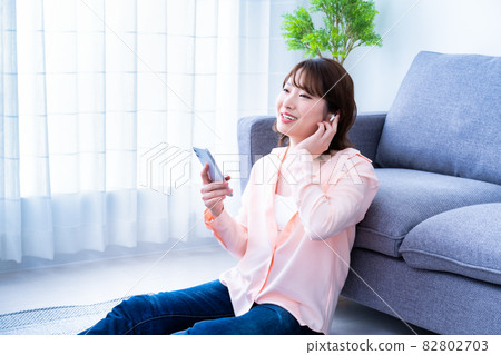 A young woman listening to music on a smartphone 82802703