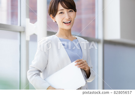 站在窗邊拿著筆記本電腦的女商人 站在窗邊拿著筆記本電腦的女商人 82805657