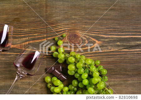 Glasses of wine and ripe grapes isolated on a wooden table 82810698