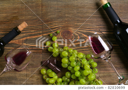 Bottles and glasses of wine, chocolate and ripe grapes on wooden background 82810699
