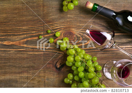 Two glasses, bottle of red wine and grape on a wooden table Two glasses, bottle of red wine and grape on a wooden table 82810713