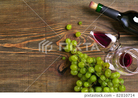 Two glasses, bottle of red wine and grape on a wooden table Two glasses, bottle of red wine and grape on a wooden table 82810714
