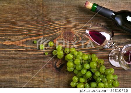 Two glasses, bottle of red wine and grape on a wooden table Two glasses, bottle of red wine and grape on a wooden table 82810716
