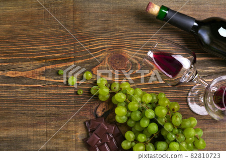Two glasses, bottle of red wine and grape on a wooden table Two glasses, bottle of red wine and grape on a wooden table 82810723