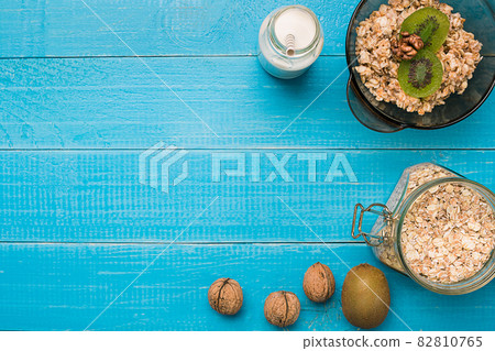 healthy breakfast with bowl of homemade oatmeal with fruits and milk over rustic wooden background. healthy breakfast with bowl of homemade oatmeal with fruits and milk over rustic wooden background. 82810765