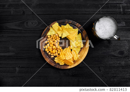 Lager beer and snacks on black wooden table. Nuts, chips. Top view with copyspace Lager beer and snacks on black wooden table. Nuts, chips. Top view with copyspace 82811413