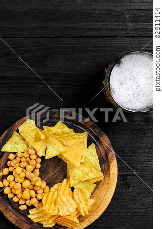 Lager beer and snacks on black wooden table. Nuts, chips. Top view with copyspace Lager beer and snacks on black wooden table. Nuts, chips. Top view with copyspace 82811414
