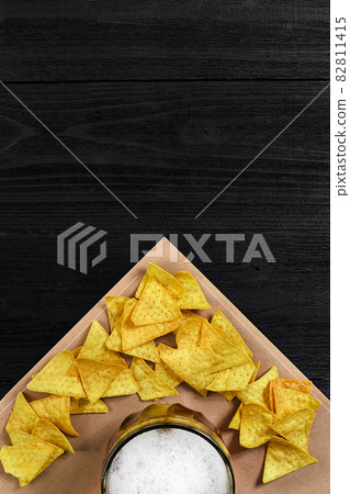 Top view of tortilla chips and glass of beer on black wooden background Top view of tortilla chips and glass of beer on black wooden background 82811415