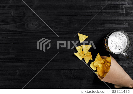 Top view of tortilla chips and glass of beer on black wooden background 82811425