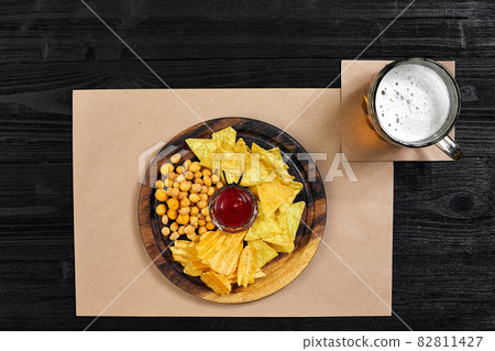Lager beer and snacks on black wooden table. Nuts, chips. Top view with copyspace Lager beer and snacks on black wooden table. Nuts, chips. Top view with copyspace 82811427