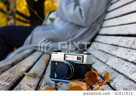 Photo camera on bench in autumn park. Photo camera on bench in autumn park. 82811815