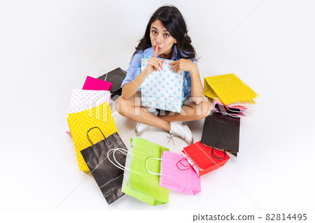 Close-up tired emotive young girl after shopping at black friday sales. Model with lots of bags, colorful bright packages Close-up tired emotive young girl after shopping at black friday sales. Model with lots of bags, colorful bright packages 82814495