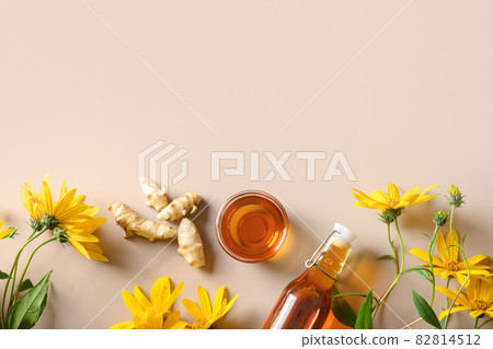 Jerusalem artichoke syrup in bottle, flowers and root. 82814512